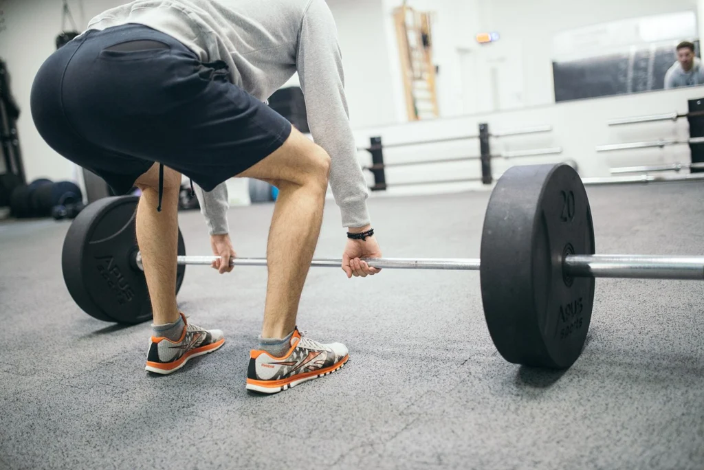 Man setting up a barbell deadlift in flat training shoes