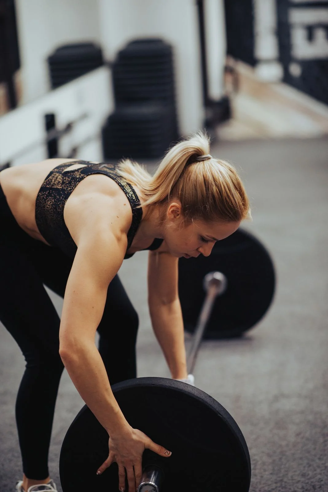 Woman gripping a loaded barbell before a deadlift