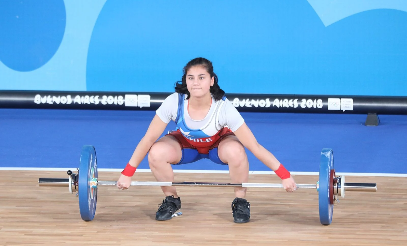 Female weightlifter gripping the bar in the snatch start position